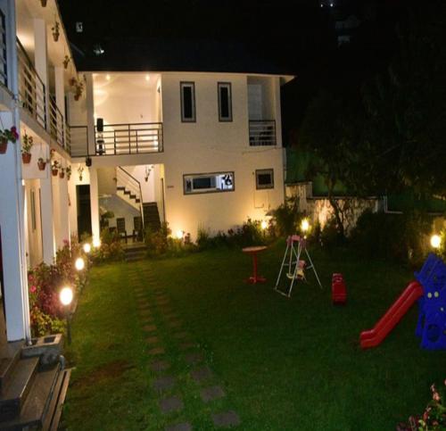 a yard at night with a house and a playground at Magizham Homestay in Kodaikānāl