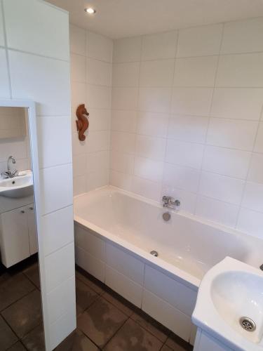 a white bathroom with a tub and a sink at The Barn in Loosdrecht
