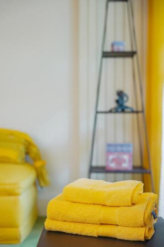 a stack of yellow towels on a table with a shelf at Chalet La Forestière in Saint-Paul-en-Chablais