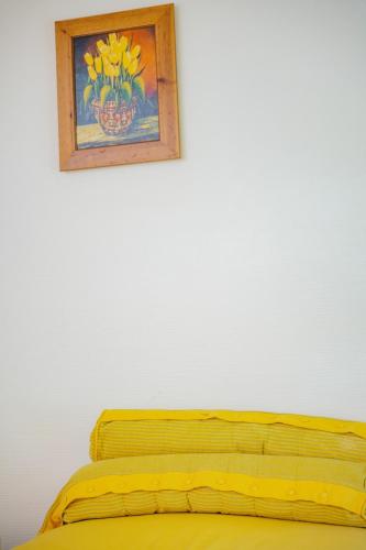 a yellow bed with a picture on the wall at Chalet La Forestière in Saint-Paul-en-Chablais