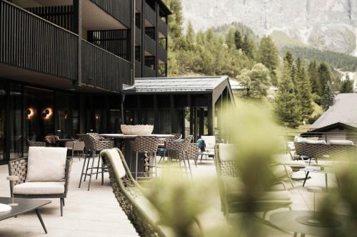 a building with chairs and tables on a patio at Hotel Plan de Gralba - das Berghotel in Selva di Val Gardena
