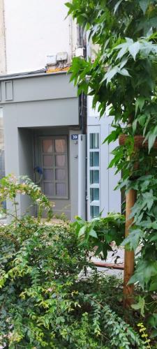 a white house with a door and some bushes at Magnifique appartement avec terrasse au centre Epinal in Épinal