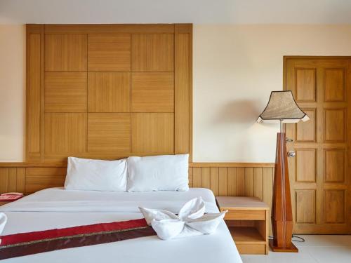 a bedroom with a white bed with a wooden headboard at Metro Point Bangkok in Bangkok