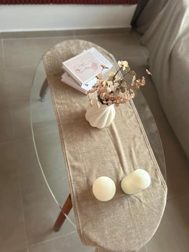 a glass table with a vase of flowers and a book at Oropos Cozy House in Néa Palátia