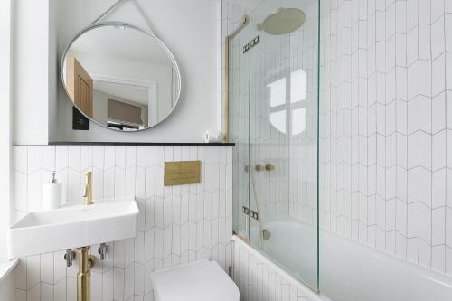 a bathroom with a shower and a sink and a mirror at Luxe 2 bed - 20 minutes from Central London in London
