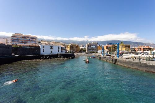 a river with boats in a city with buildings at Estudio céntrico La Marina in Puerto de la Cruz