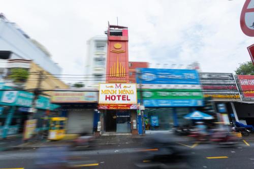 eine belebte Stadtstraße mit einem Gebäude mit einem Uhrenturm in der Unterkunft Minh Hồng Hotel in Ho-Chi-Minh-Stadt