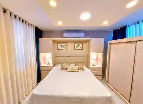 a bedroom with a large white bed and two lamps at Ammoun Luxury Apartments 1 in Amman
