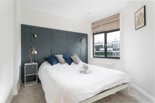 a bedroom with a large white bed with blue pillows at Luxe 2 bed - 20 minutes from Central London in London