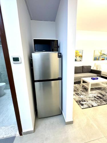 a kitchen with a stainless steel refrigerator with a microwave at Newly Furnished, Bright and Spacious Studio in France Cluster, International City in Dubai