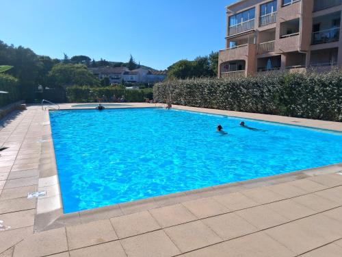 two people swimming in a large blue swimming pool at Domaine du Préconil in Sainte-Maxime