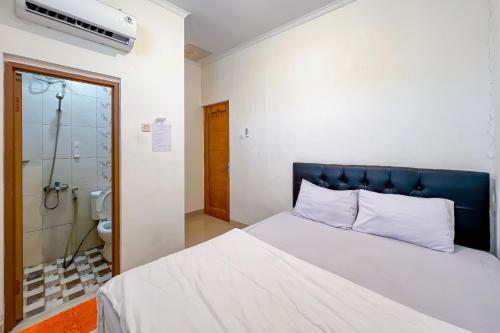 a bedroom with a bed with a blue headboard and a shower at JJ House Mitra RedDoorz in Jakarta