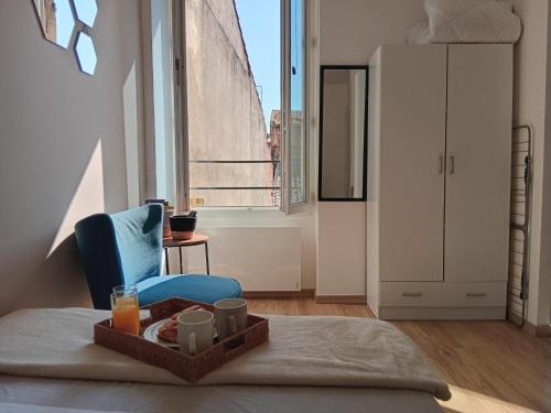 a room with a bed and a blue chair with a tray of food at Les Apparts de Marmande - Petit Cocon en ville in Marmande