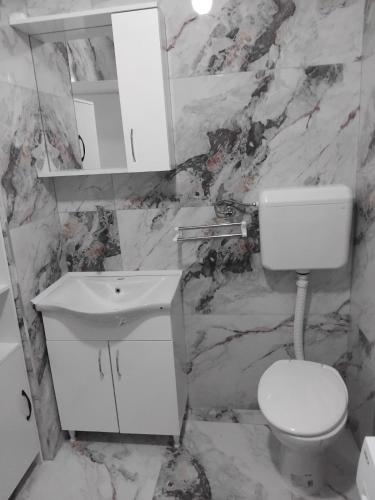 a white bathroom with a toilet and a sink at Nadica Apartment in Struga