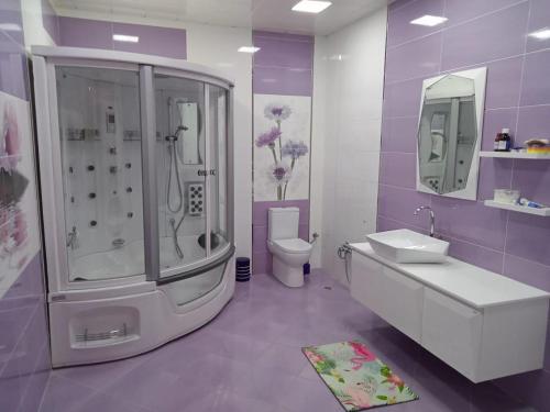 a purple and white bathroom with a shower and a sink at Super Villa in Mardakan