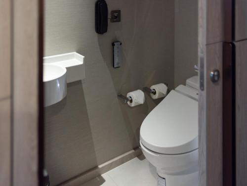 a bathroom with a toilet and a phone on the wall at Hotel Nikko Bangkok in Bangkok