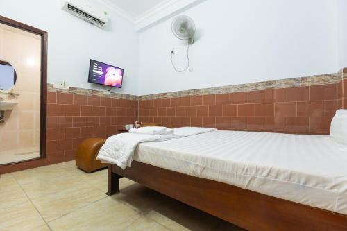 a bedroom with a bed and a tv on the wall at Minh Hồng Hotel in Ho Chi Minh City