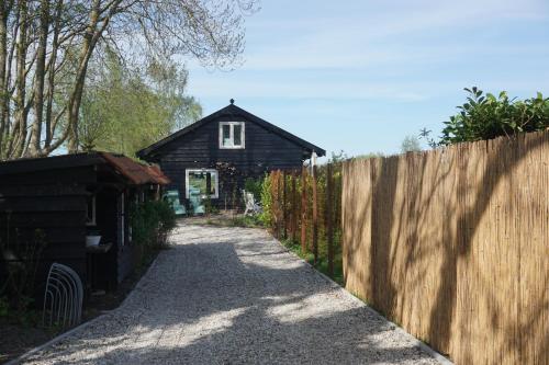 a small house with a fence next to a driveway at The Barn in Loosdrecht