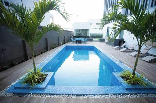 ein Pool mit Palmen auf einem Gebäude in der Unterkunft Bright Modern2 bedroom Apr3 minutes away from a&c mall EAST LEGON in Trofwi
