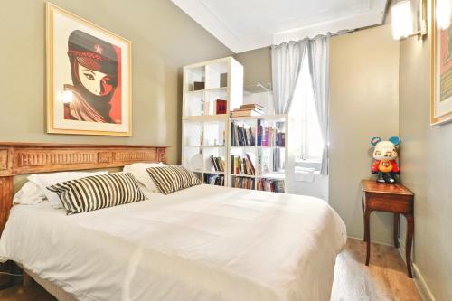 a bedroom with a white bed and a book shelf at Le jardin de Ponteves in Aix-en-Provence