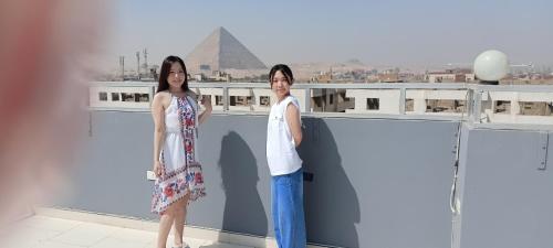 two people standing on a roof with the pyramid at Phoenix Pyramids View Inn in Cairo