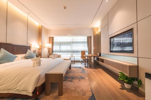 a hotel room with a large bed and a flat screen tv at Changzhou Wenpu Hotel Changzhou Culture Square Branch in Changzhou