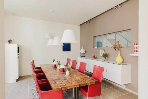 a dining room with a table and red chairs at B&B Asinello in Bruges