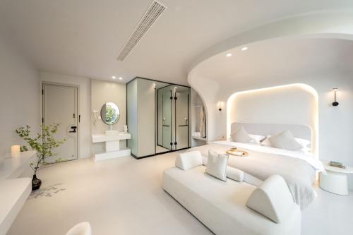 a white bedroom with a white bed and a white couch at Dali Santorini Yuexin Seaview Hotel in Dali Airport