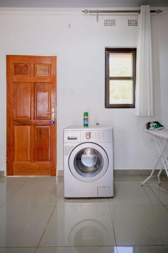 a washing machine in a room with a door at Villa Stone Apartments in Lusaka