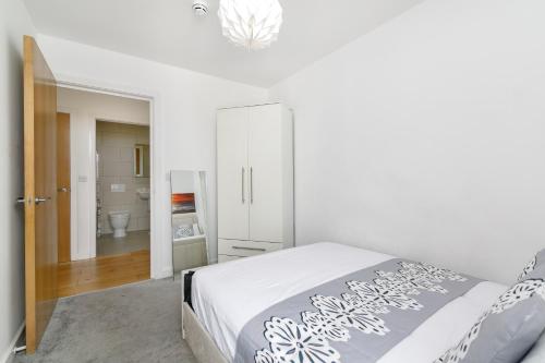 a white bedroom with a bed and a bathroom at 2 Bedroom Apartment near City Airport in London