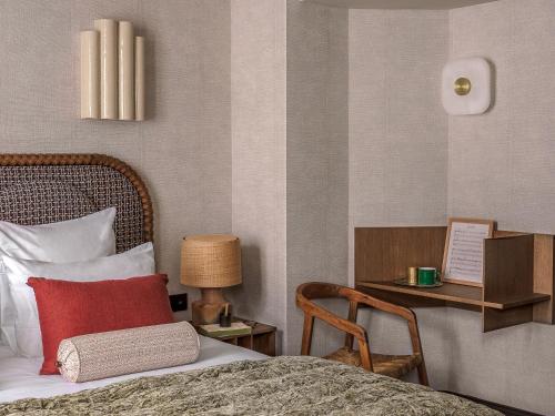 a bedroom with a bed with a red pillow and a chair at Hotel Suzie Blue in Paris