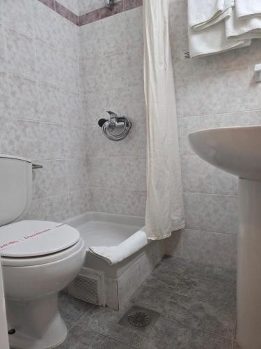 a white bathroom with a toilet and a sink at Odysseus Hotel in Paleokastritsa