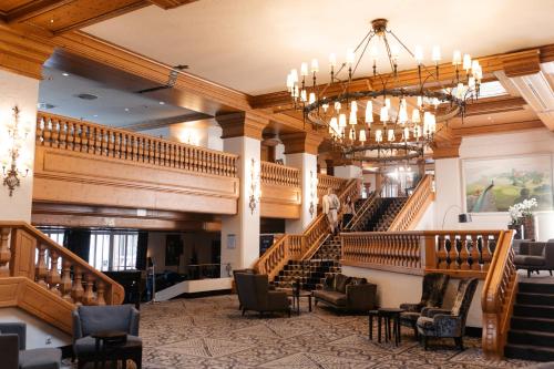 a large lobby with stairs and a chandelier at Hotel Maximilian in Bad Griesbach