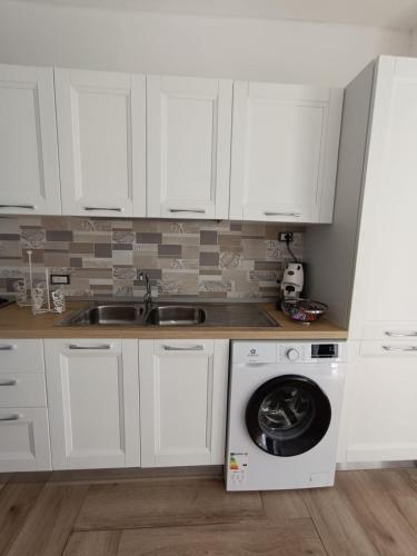 a kitchen with white cabinets and a washing machine at Solleone - Appartamento 4B in Paestum