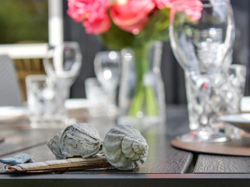 a wooden table with a vase of flowers and some vegetables at Holiday Home Salgarth - 450m from the sea by Interhome in Sæby