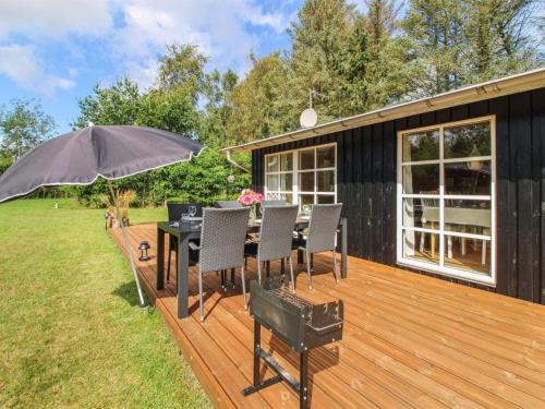 a deck with a table and chairs and an umbrella at Holiday Home Salgarth - 450m from the sea by Interhome in Sæby