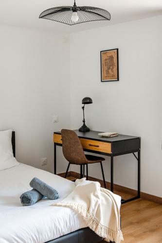 a bedroom with a desk and a bed with a chair at Léna 2 chambres Jardin- climatisation Netflix in Saint-Just-Saint-Rambert