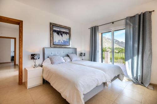 a bedroom with a large bed and a large window at Spacious villa for 10 with private pool in El Port