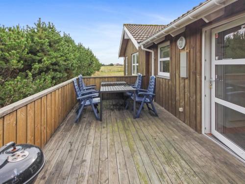 a wooden deck with two chairs and a table at Holiday Home Calina - 300m from the sea by Interhome in Sæby