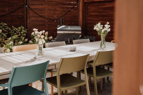 a table with chairs and vases with flowers on it at Coś miłego in Gowidlino