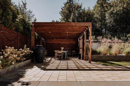a wooden pergola with a table in a garden at Coś miłego in Gowidlino