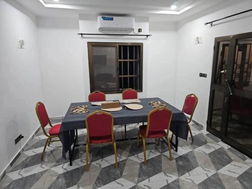 a dining room with a blue table and red chairs at 2 cozy bedrooms in Lomé Sagbado in Komé