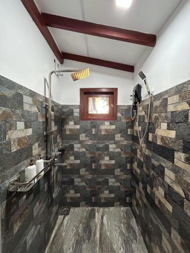 a bathroom with a shower and a stone wall at Villa Rice Edge in Matara