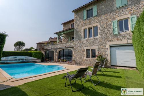 a house with a swimming pool and two chairs in the yard at Gite près des gorges du Tarn et du viaduc de Millau in Compeyre