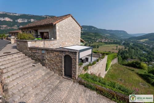 a small stone building on a hill with mountains in the background at Gite près des gorges du Tarn et du viaduc de Millau in Compeyre