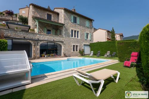 a villa with a swimming pool in front of a house at Gite près des gorges du Tarn et du viaduc de Millau in Compeyre