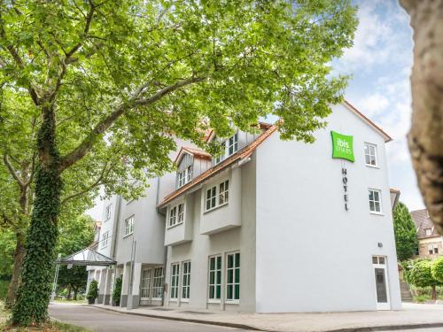 a white building with a green sign on it at ibis Styles Neckarsulm in Neckarsulm