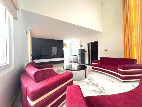 a living room with two red couches and a television at Quad Club - Resort and Spa, Nandi Hills in Nandigunda
