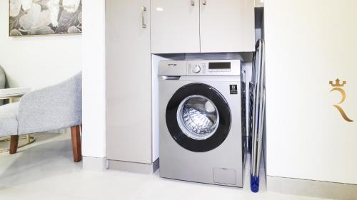 a white washing machine in a room with a chair at 2BR Waterfront Lamar Residences Abu Dhabi in Al Qurayyah