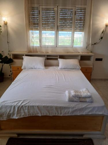 a large bed with white sheets and two windows at Kariat arkma in Nador